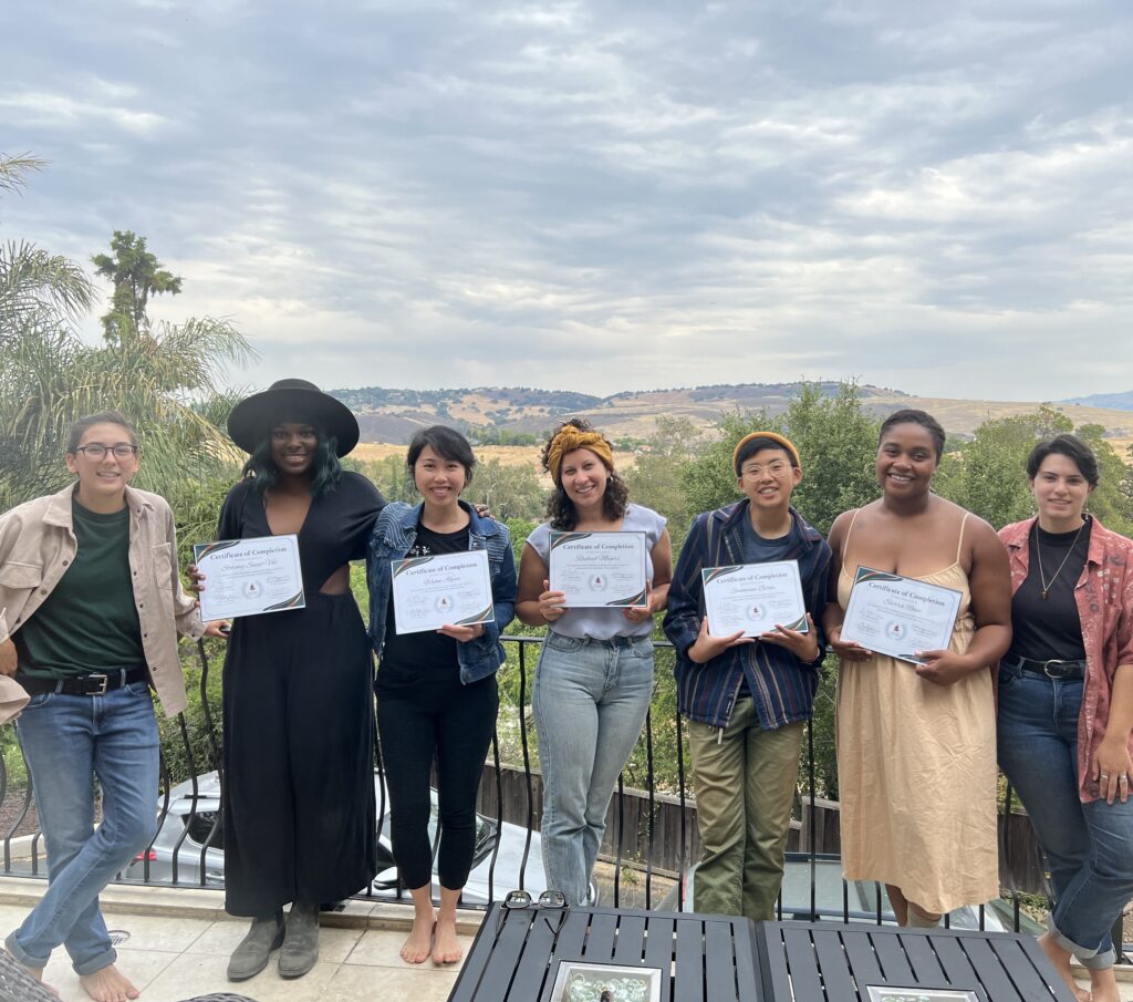Five members of the Pathfinders cohort pose with their certificates. Standing next to them in each side are Justice Outside team members Dylan Kennedy and Lau Hernandez. 