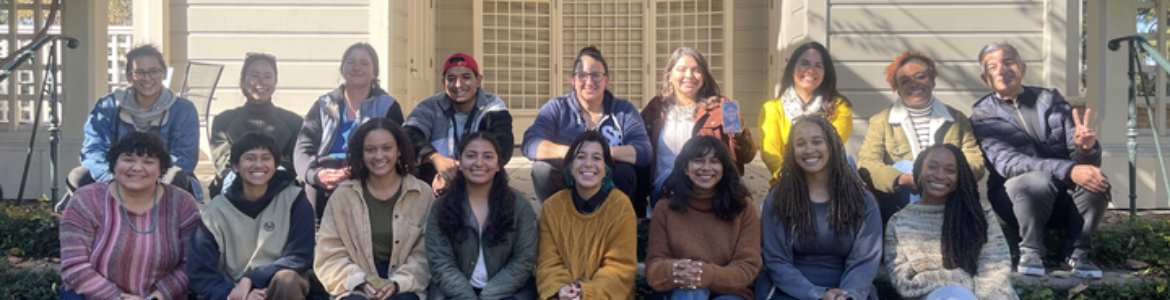 Group photo of some of our Rising Leaders fellows, facilitators, and Justice Outside's Program Associate, Dylan Kiyo Kennedy. They are sitting in two rows on concrete steps.