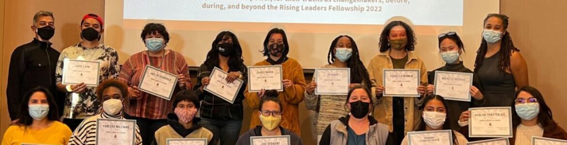 Group photo of facilitators with some of our Rising Leaders Fellows holding up their certificate of completion. Behind them is a screen projected that reads, "Thank You Rising Leaders Fellowship" and their names listed below.
